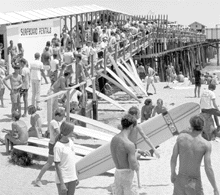 Surfing craze at the pier 1960s men and women stand around the pier with their surf boards ready to surf the day away